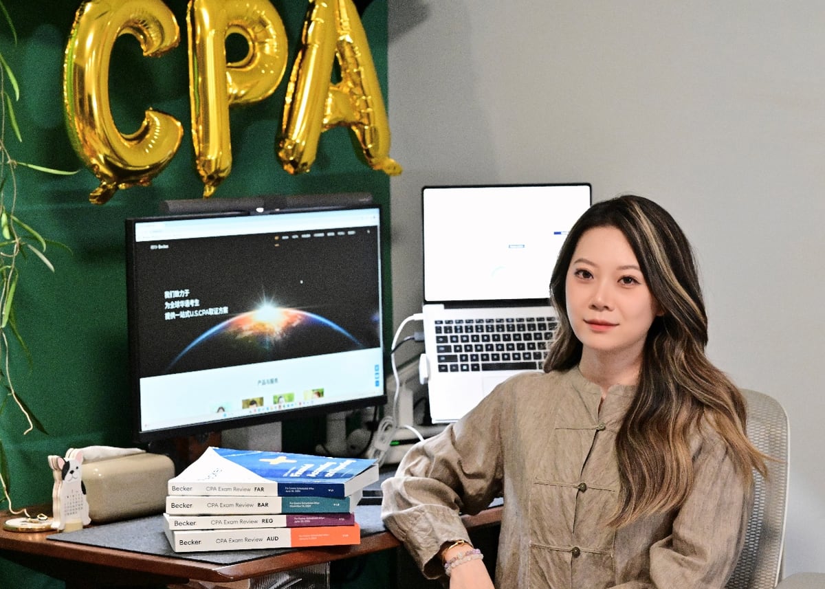 樊同学家居书桌合影：手书背景金色 CPA 气球字 + Becker 教材塔 + 双屏备考工作站