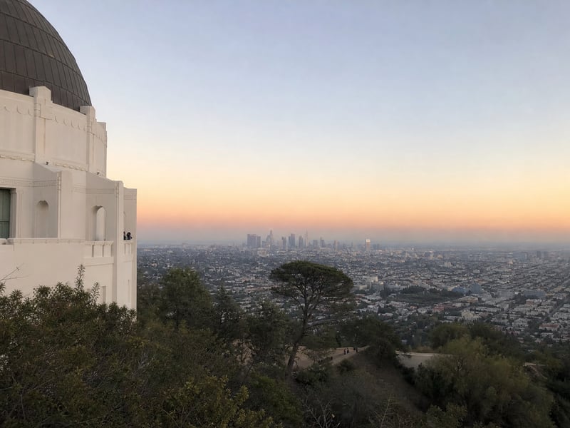 Griffith Observatory + 洛杉矶 downtown 黄昏天际线，紫橙渐变夕阳与城市灯光